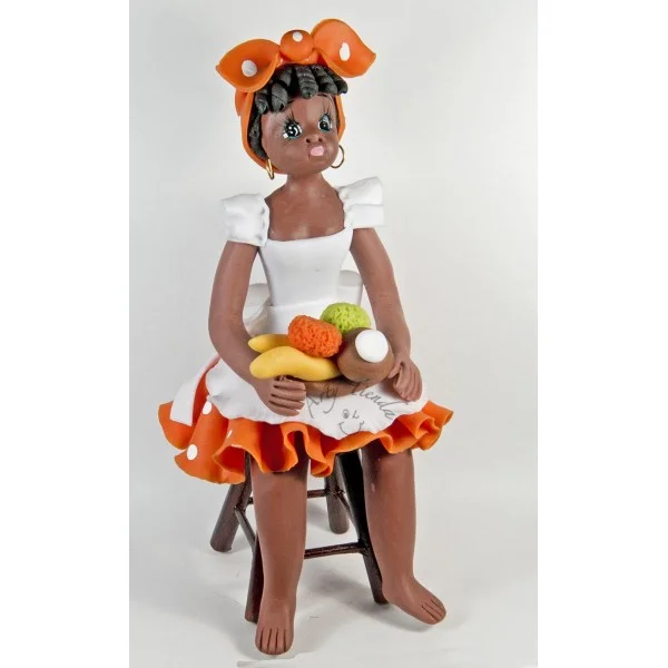 Figura artesanal de una mujer palenquera sentada con traje tradicional y una bandeja de frutas.